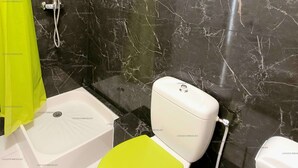 Un baño con inodoro blanco, cortina de ducha verde y salpicadero de mármol.