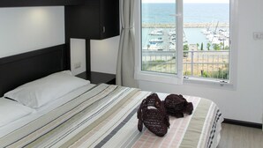 A bedroom with a bed, a window with a view of a marina, and a curtain. - Cosy apartment in villa for 4 people with WIFI, A/C, TV, terrace and pets allowed (San Lorenzo Al Mare)