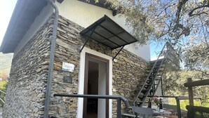 A stone building with a metal staircase, a door, and outdoor seating. - Lovely apartment for 4 guests with pool, WIFI, patio, pets allowed and panoramic view (Dolcedo)