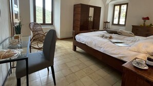 A bedroom with a bed, a chair, a table with a cup and a jar, and a dresser.