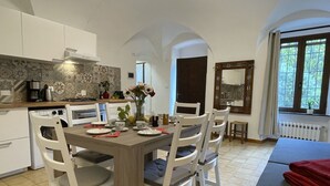 A modern kitchen with white cabinets, a dining table set for four, and a large window with a view of greenery.