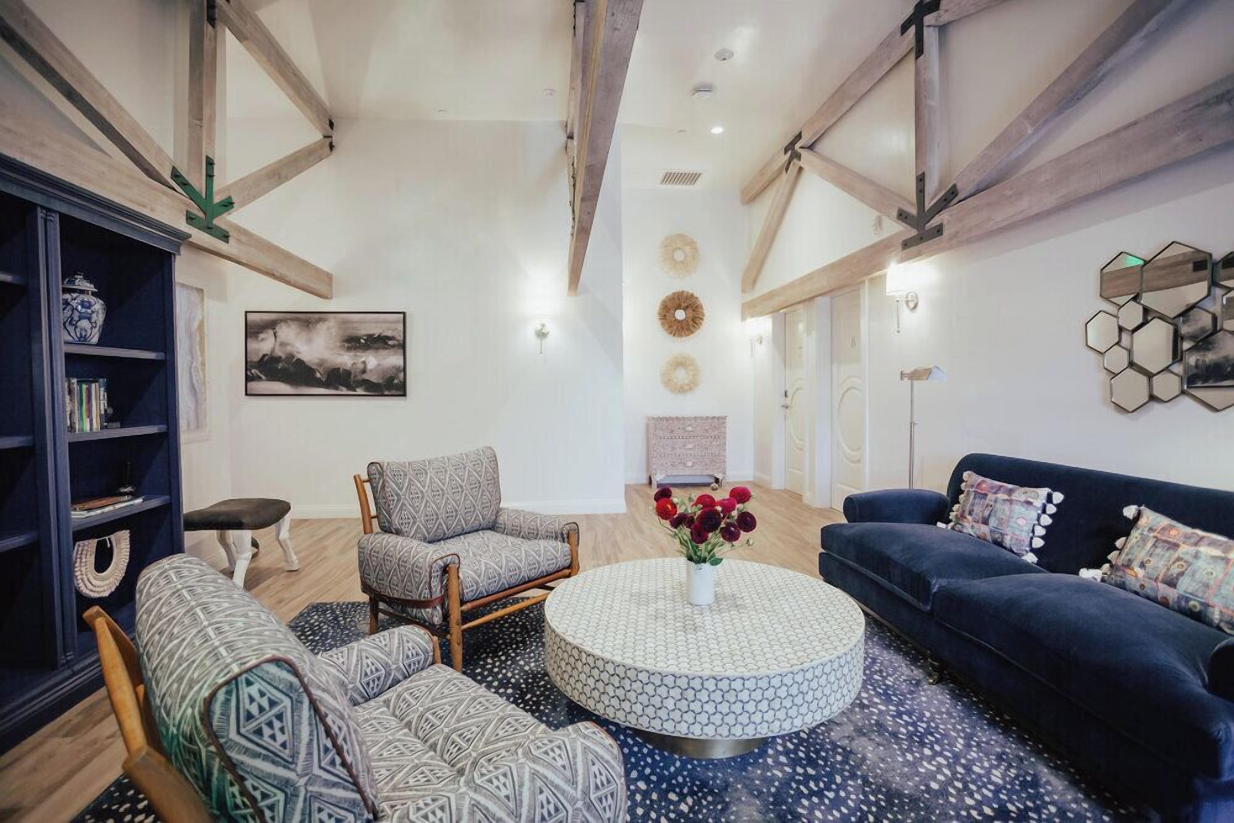 A spacious living room with a round coffee table, patterned sofas, and a dark blue couch.