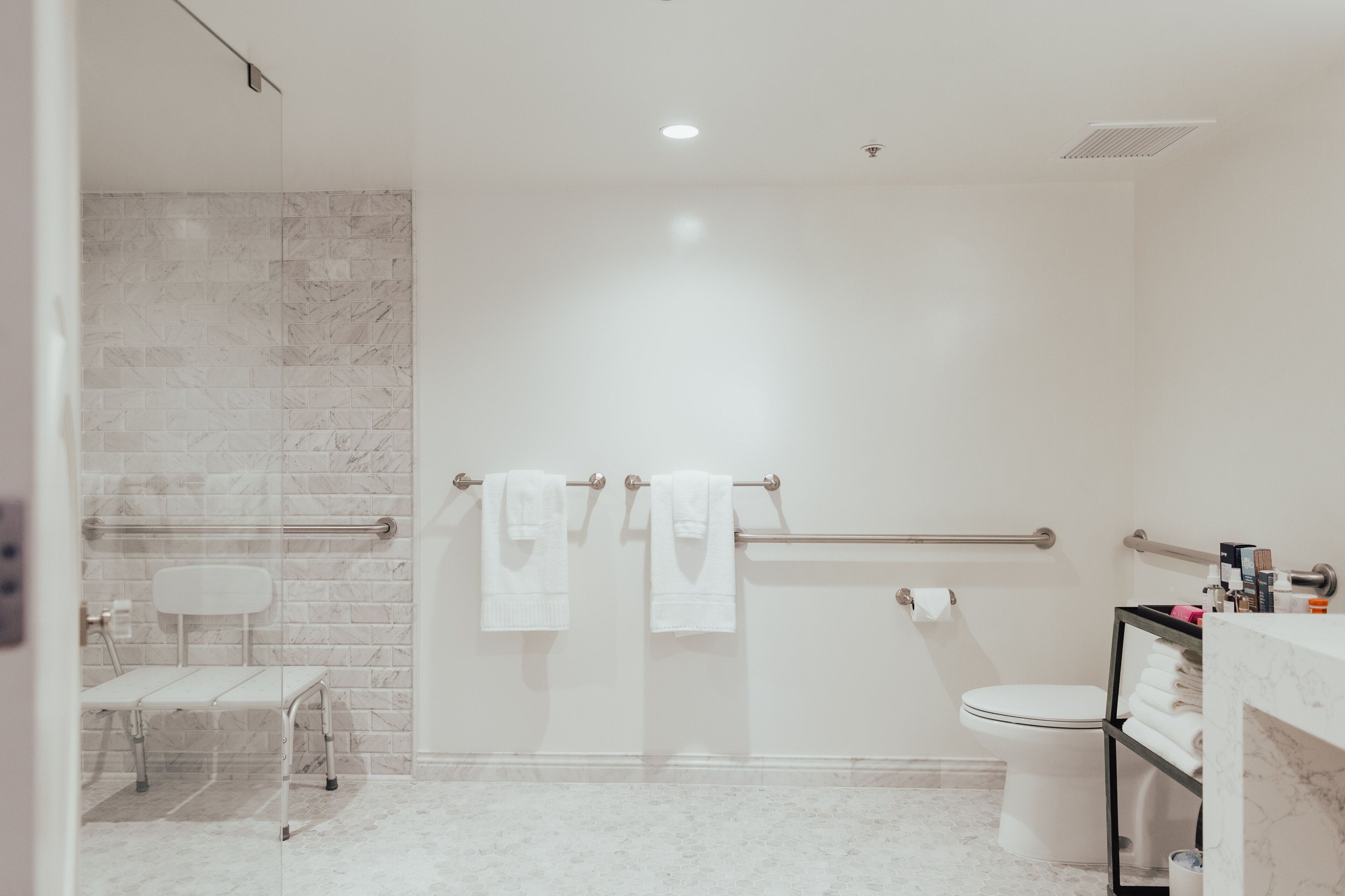 A modern bathroom with a shower, toilet, and a glass-enclosed bench.