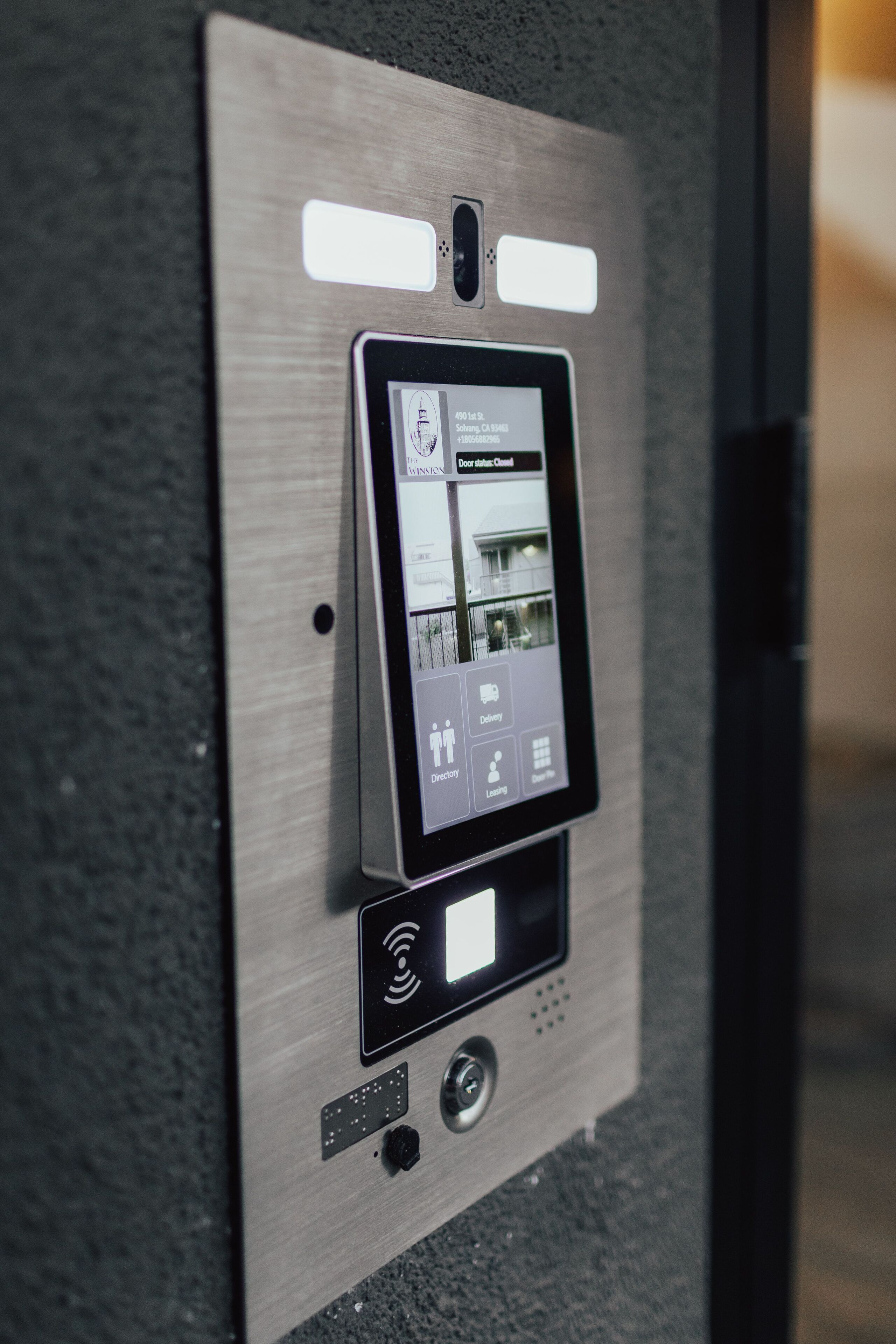 Lector de llave digital con pantalla que muestra el estado de una puerta y un icono de entrega.