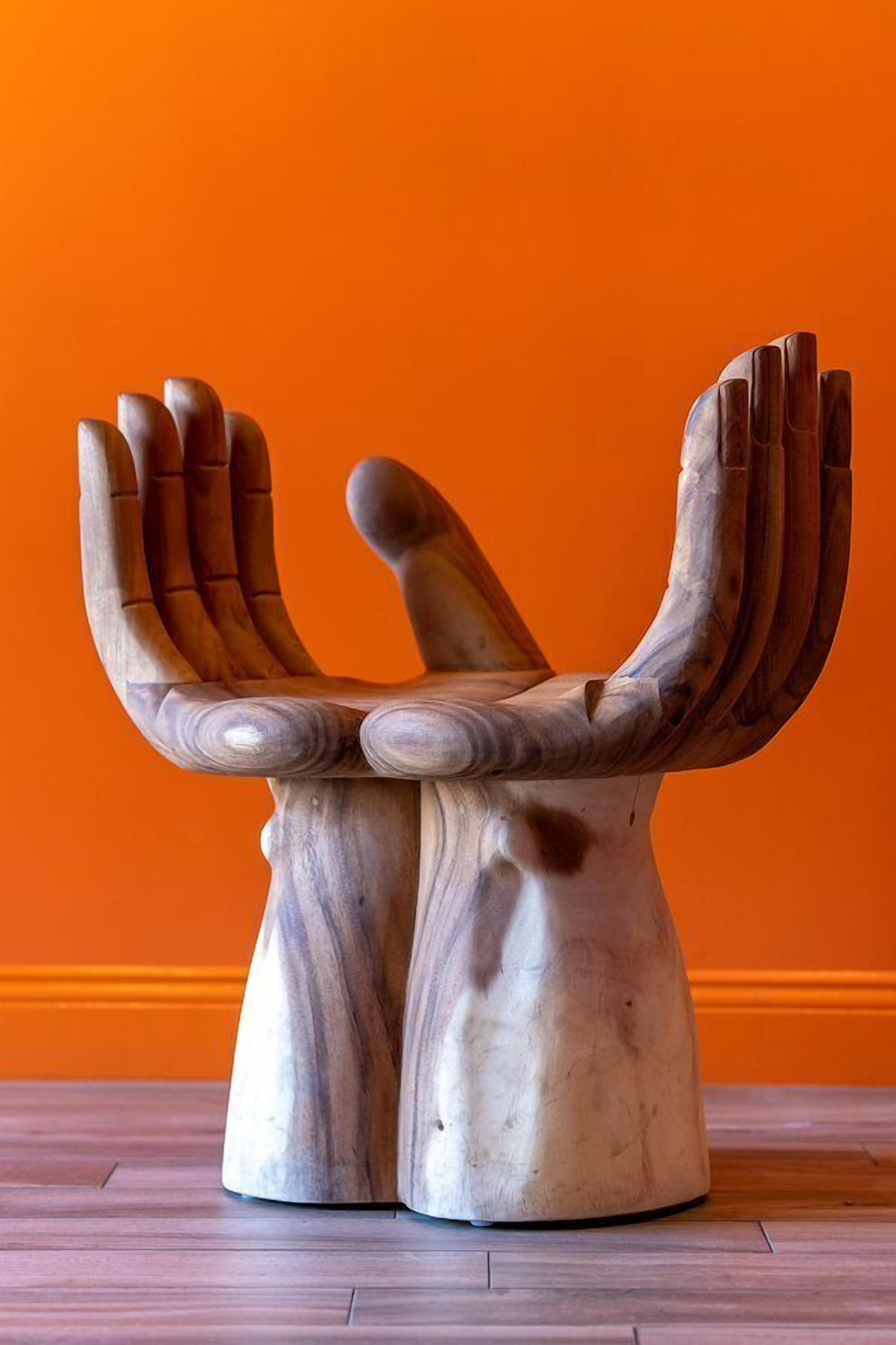 A wooden bench with a unique design against an orange wall.