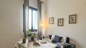 A dining area with a table set for two, a sofa, and a lamp. - Nice apartment for 3 people with pool, WIFI, patio, pets allowed and panoramic view (Lecchiore)