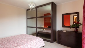 Une chambre à coucher avec un lit, une commode, un miroir et un lustre.