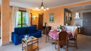 Un salon chaleureux avec un canapé bleu, une table à manger avec des chaises et un coin cuisine équipé d’une cuisinière.