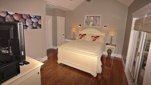 Ein Schlafzimmer mit einem Bett, zwei Nachttischlampen, einem Deckenventilator, einem Fernseher und einem Bild an der Wand.