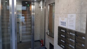 Eine Hotelhalle mit Panoramaaufzug, Feuerlöscher und einer Reihe von Postfächern.