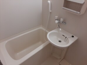 A bathroom with a white bathtub, a sink, and a towel rack.