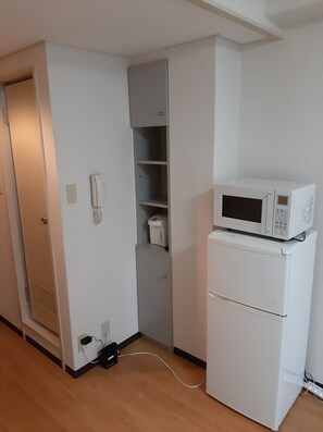 A compact kitchenette with a microwave, a small refrigerator, and a built-in oven.