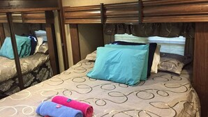 A bedroom with a bed, pillows, and rolled towels. - Camper at the Sequoia Forest Retreat (Badger)