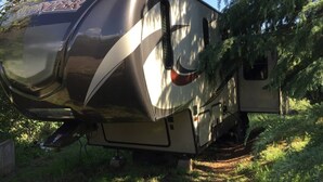 A recreational vehicle parked in a wooded area. - Camper at the Sequoia Forest Retreat (Badger)