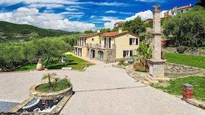 A Mediterranean-style villa with a stone facade, a central courtyard, and a view of the surrounding hills. - Nice apartment in villa for 4 guests with WIFI, TV, patio, pets allowed and panoramic view (Imperia)