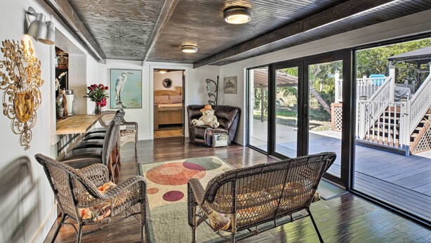 A spacious living area with a dining table, wicker chairs, a large rug, and a view of the outdoor deck. - Pet-Friendly Oasis w/ Deck & Fire Pit in Bokeelia! (Bokeelia)