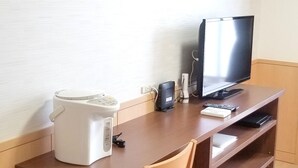 Una habitación pequeña con escritorio de madera, televisión y microondas.