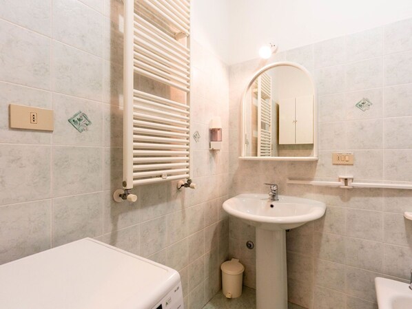 A bathroom with a white sink, a mirror, a towel rack, and a toilet.
