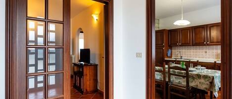 Eine Küche mit Holzausstattung, einem Esstisch mit Blumenmuster-Tischdecke und einem Fernseher im Hintergrund.