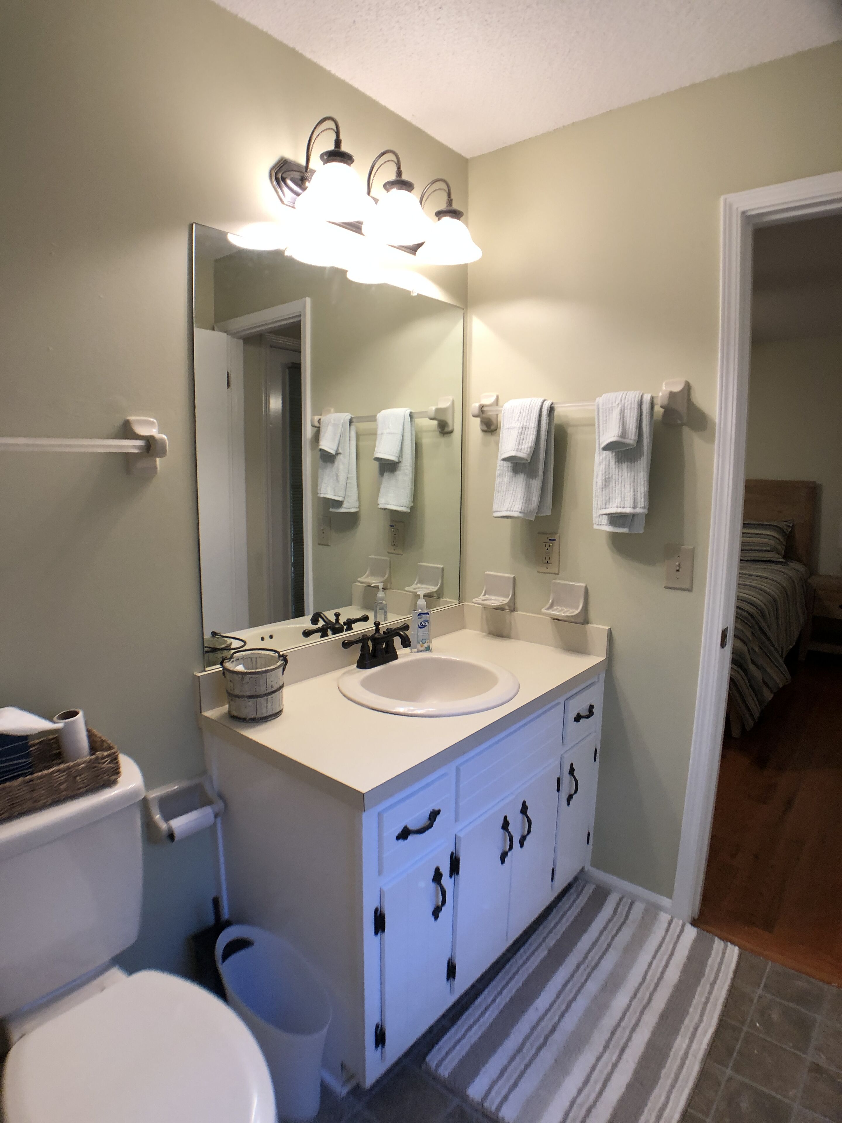 A bathroom with a white sink, a mirror, and a towel rack.