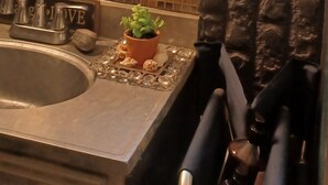 Une cuisine avec un évier, une petite plante en pot et une fenêtre ornée de vitraux colorés.