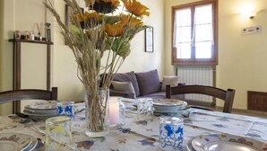A dining table set with plates, glasses, and a vase with dried plants. - Lovely apartment for 4 people with WIFI, TV, patio, pets allowed and panoramic view (Vendone)