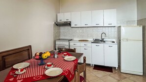 A compact kitchen with white cabinets, a stove, a sink, and a refrigerator. - Cosy apartment for 5 guests with WIFI, TV, terrace and pets allowed (Pietra Ligure)