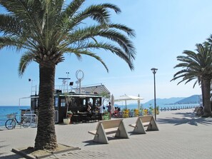 Un café en bord de mer avec une terrasse, des palmiers et une vue sur l’océan.