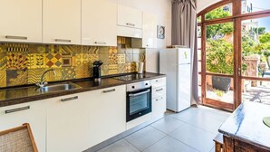 A modern kitchen with patterned backsplash, white cabinets, stainless steel sink, and a view of a garden through a large window. - Beautiful apartment for 5 people with A/C, WIFI, TV and patio (Finale Ligure)