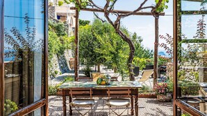 A patio with a table and chairs, surrounded by greenery and a pergola. - Beautiful apartment for 5 people with A/C, WIFI, TV and patio (Finale Ligure)