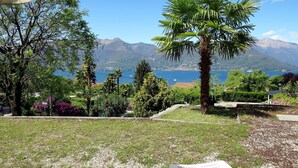 A view from a terrace with a pool, overlooking a lake and mountains.