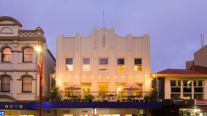 A historic building with a balcony, multiple windows, and outdoor seating with umbrellas. - Alabama Hotel Hobart (Hobart)