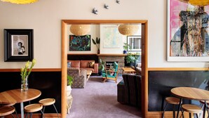 A cozy interior with a wooden dining area, a sofa, and a fireplace. - Alabama Hotel Hobart (Hobart)