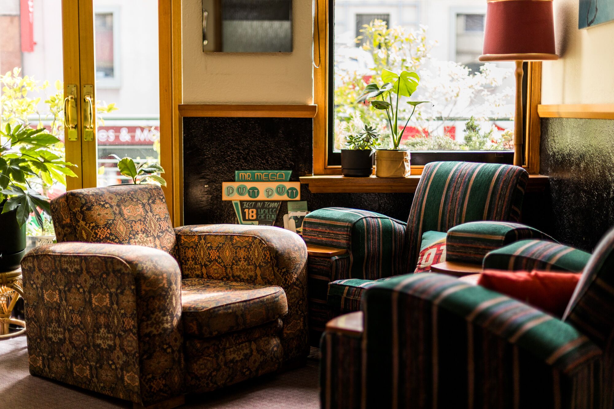 A cozy seating area with patterned armchairs and a striped sofa, a small table, and a fireplace with a sign above it.