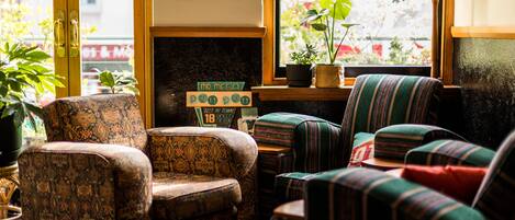A cozy seating area with patterned armchairs and a striped sofa, a small table, and a fireplace with a sign above it.