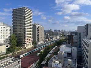 A high-rise building with a modern design, surrounded by other buildings and a train track. - APA Hotel Omori Ekimae (Tokyo)