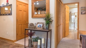 A hallway with a wooden door, a mirror, a console table with decorative items, and a sign on the wall. - Cozy Cabin 2 - A Great Holiday Family Place - Come Play and Stay! (Branson)