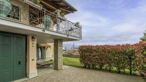 Ein zweistöckiges Haus mit Balkon, grüner Tür und gepflastertem Innenhof.