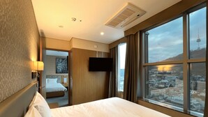 Habitación de hotel con una cama grande, un televisor en la pared y una ventana con vistas a la ciudad.