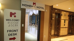 La entrada al HOTEL MOHENIC en Seúl, con un cartel de recepción y un ascensor.