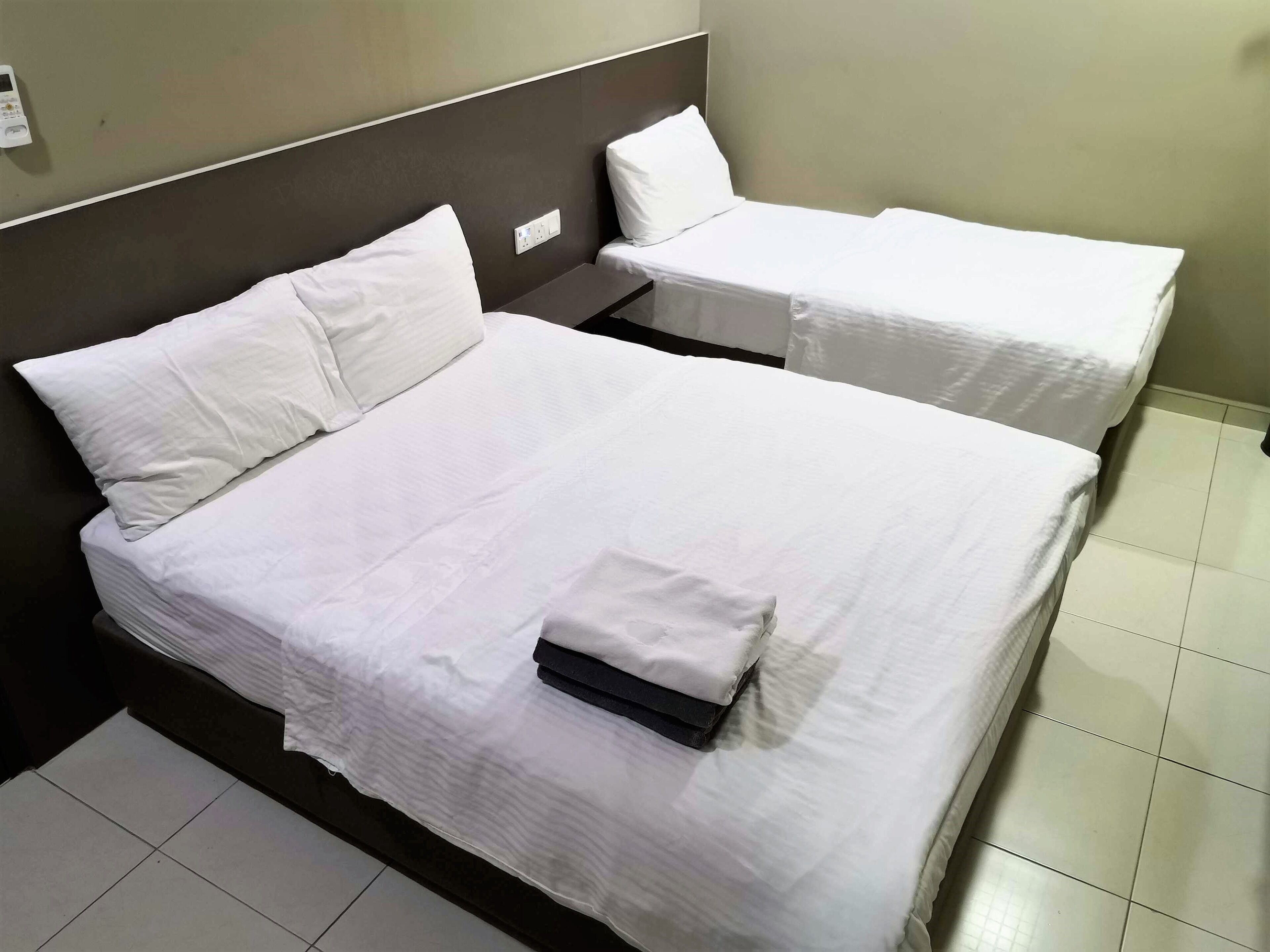 Une chambre d’hôtel avec deux lits, chacun étant équipé de draps et d’oreillers blancs.