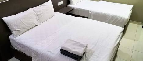 Une chambre d’hôtel avec deux lits, chacun étant équipé de draps et d’oreillers blancs.