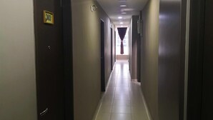 A long, narrow hotel corridor with doors on both sides, a tiled floor, and a ceiling with recessed lighting. - Tropika Garden Hotel Kulai (Kulai)