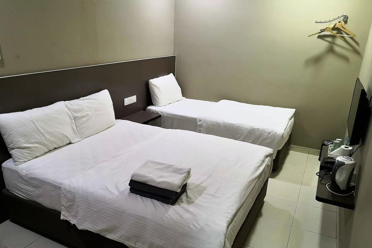 Une chambre d’hôtel avec deux lits, un téléviseur à écran plat, une machine à café et une serviette sur le lit.