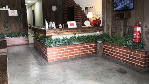 A reception area with a brick counter, a clock, a television, and a fire extinguisher. - Tropika Garden Hotel Kulai (Kulai)
