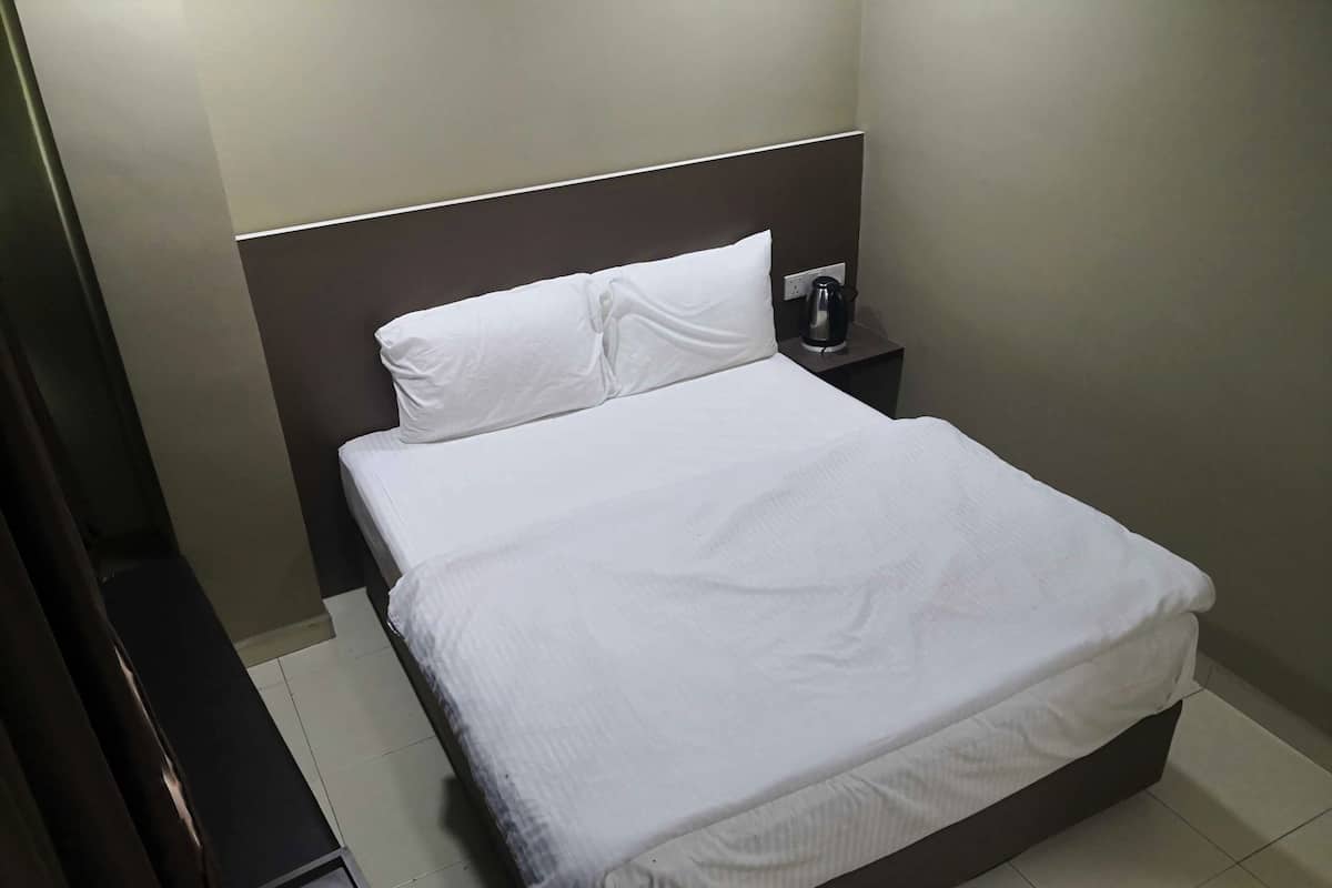 Un lit bien fait, avec du linge de lit blanc, dans une chambre d’hôtel.