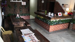A rustic outdoor seating area with wooden benches and a brick counter. - Tropika Garden Hotel Kulai (Kulai)