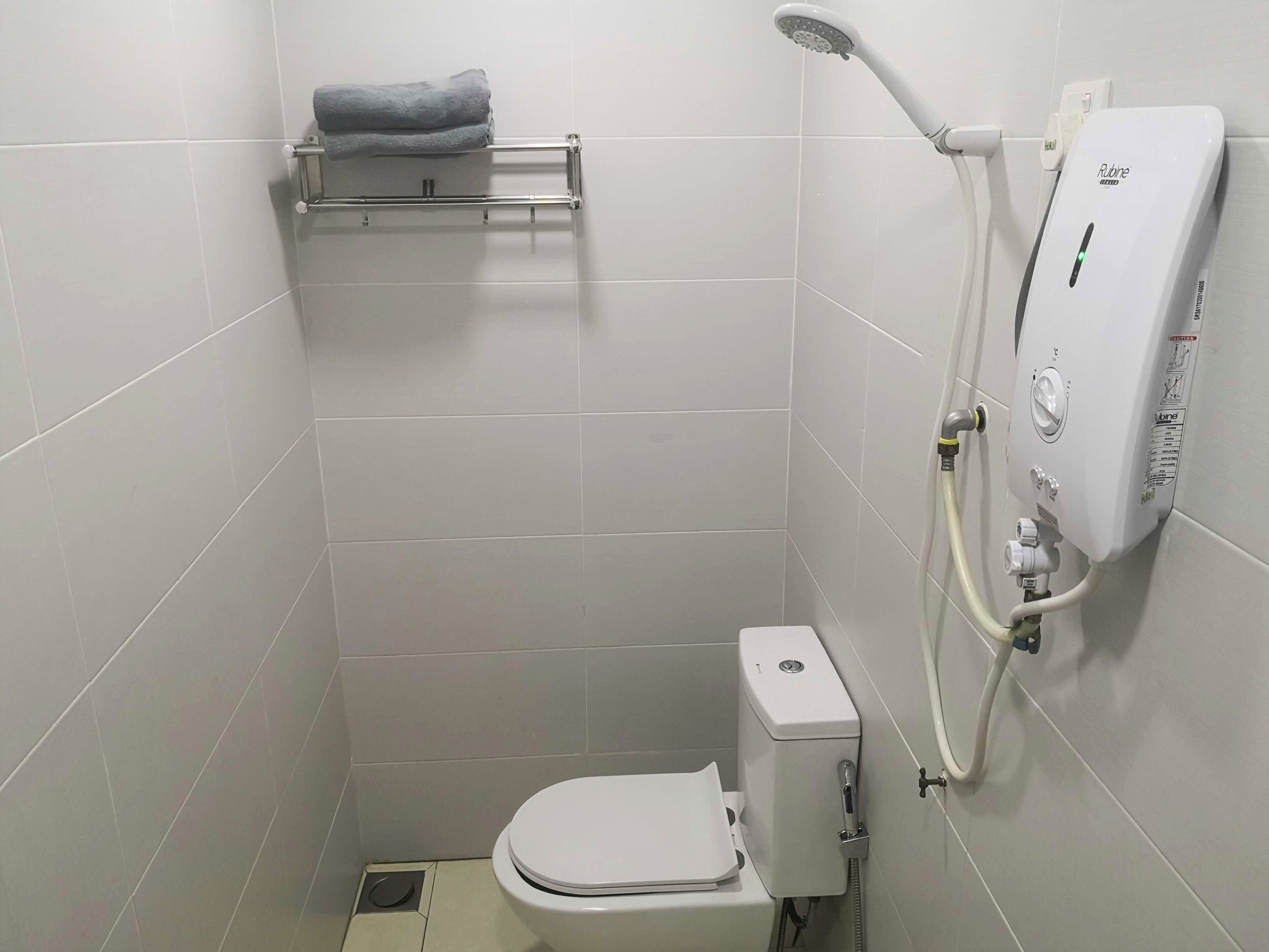 A small, modern bathroom with a toilet, a shower with a handheld showerhead, and a towel rack.