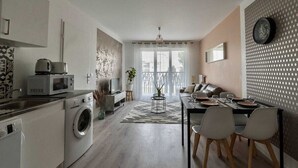 Una cocina moderna con lavadora, microondas y comedor con mesa dispuesta para dos.