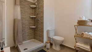Un baño moderno con ducha, inodoro y un estante con toallas.